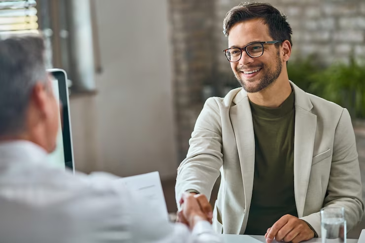 Homem sorridente em uma reunião de negócios prestes a apertar a mão, simbolizando uma negociação Click to call bem-sucedida.