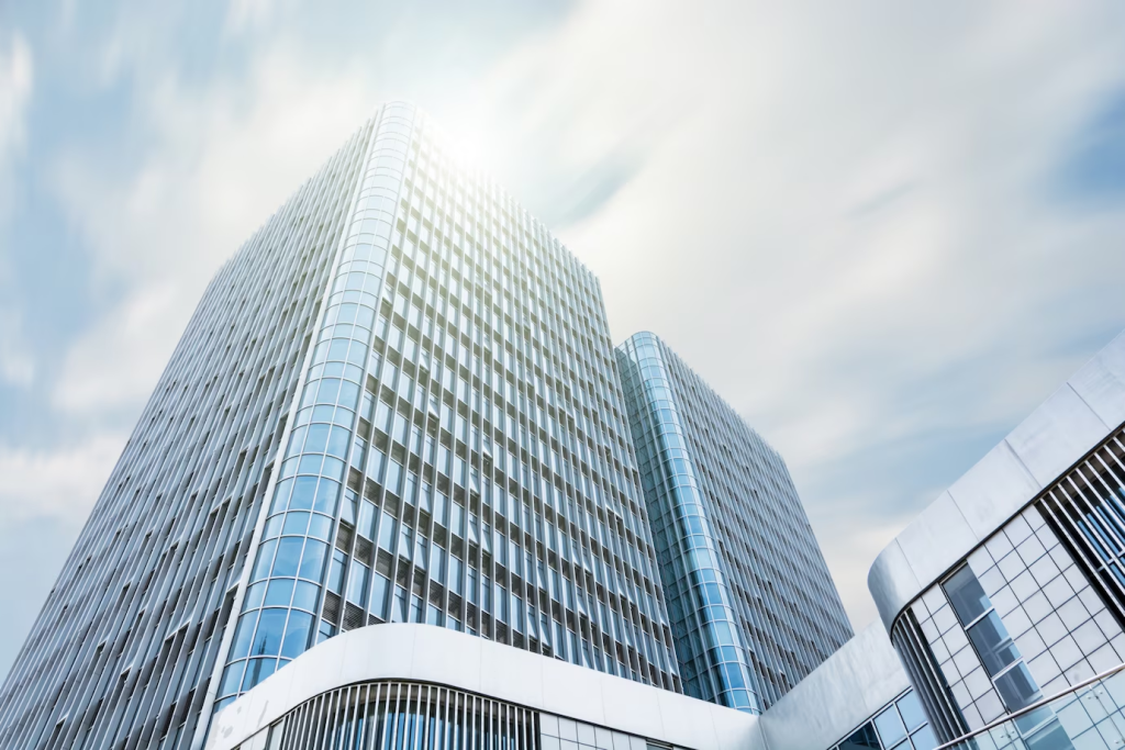 Fotografia de um edifício de escritórios moderno com fachada de vidro refletindo o céu azul, representando a presença corporativa e infraestrutura física que pode ser complementada ou substituída por soluções de telefonia virtual.