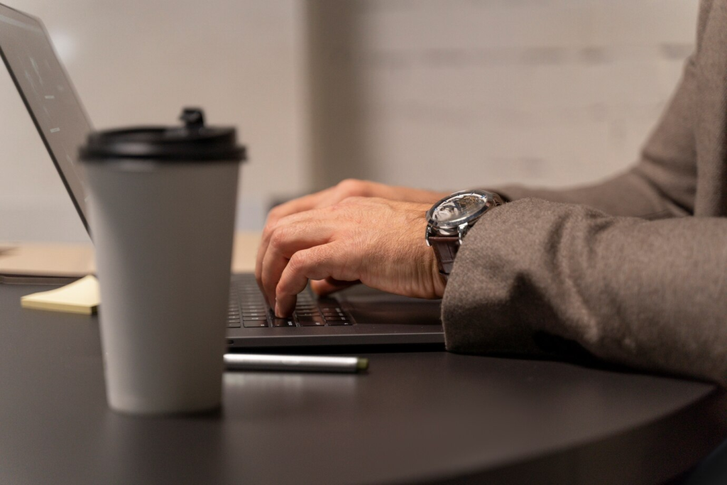 Profissional concentrado digitando em um laptop em um ambiente de escritório moderno, simbolizando foco e dedicação no trabalho.